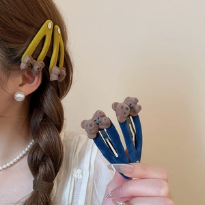 Detail showing plush bear hair clips in yellow and blue colors on a model's hair