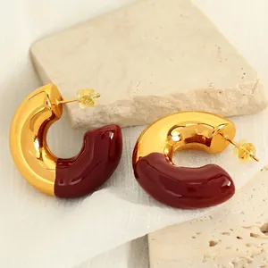 18k gold plated C-shape earrings with burgundy enamel on textured stone background