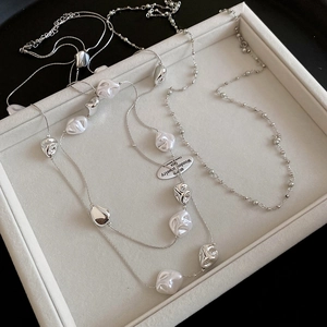 Detail of silver layered necklace with irregular beads and pendants on velvet tray
