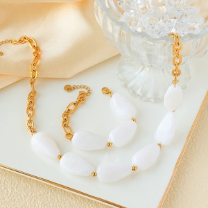 Detail of gold chain necklace and bracelet with white natural stones in a luxury tray