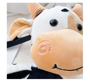 Macro view showing soft plush fabric texture and cute embroidered cow facial details