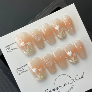 Handmade press-on nails featuring peach gradient base and delicate white tulip floral art