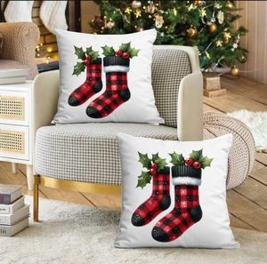 Détail de deux housses de coussin de Noël avec chaussettes à carreaux rouges sur tissu blanc