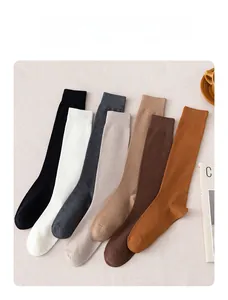 Detail view of seven pairs of plain calf socks in autumn earthy tones on fabric background