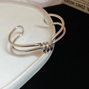 Close-up of polished irregular twisted metal bangle with silver finish and open design