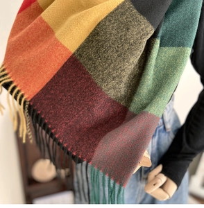 Close-up detail of vintage plaid scarf texture featuring classic tassels and knit fringe