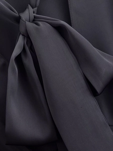 Close-up of elegant black fabric bowknot detail on a stylish women's dress or blouse