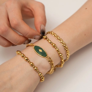 Set of four gold-tone titanium bracelets with African jade stones on female wrist