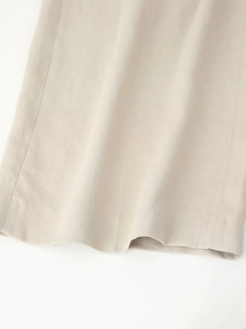 Close-up of beige linen texture and hem stitching on sleeveless vest and trouser set