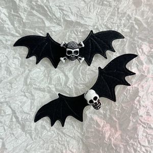 Detailed view of Halloween bat wing hair clips with white skull centers on white texture