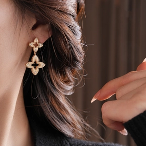 Detail of gold floral earrings with diamond accents worn by a model in soft lighting