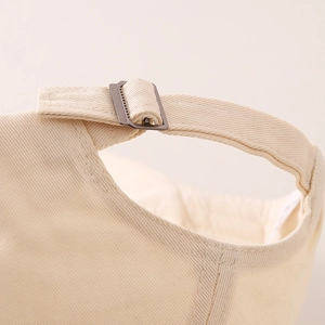 Macro shot of adjustable metal buckle and twill cotton strap on beige kids' baseball cap