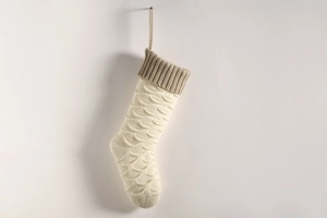 Detail of knitted Christmas stocking with fish scale texture in cream and khaki