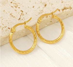 Macro detail of gold-plated twisted hoop earrings with a secure lever-back closure