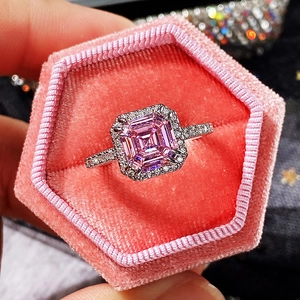 Macro detail of square pink diamond ring with halo setting on pink velvet background