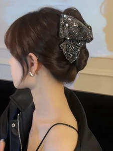 Close-up of sparkling rhinestone bow hair claw clip worn on a woman's elegant updo hair