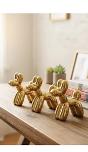 Vista dettagliata di tre sculture a forma di cane palloncino dorato con finitura a specchio