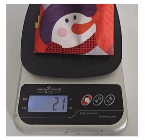 Detail of Christmas snowman fabric ornament being weighed on a scale showing 21g mass