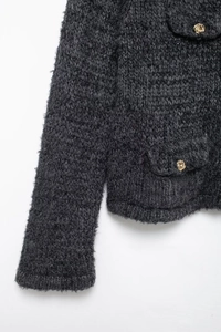 Gros plan d'un gilet en tricot gris foncé avec texture et boutons dorés décoratifs