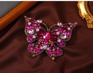 Detailed macro shot of vintage butterfly brooch with pink rhinestones on silk fabric