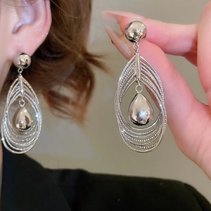 Detail view of silver layered oval hoop earrings with a central mirror teardrop pendant