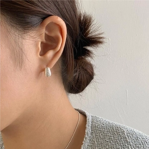 Close-up of minimalist 925 silver stud earring with elegant spiral texture on model