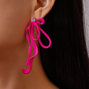 Close-up of bright pink ribbon earrings with rhinestone accent on model's ear