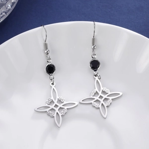 Silver Celtic knot earrings with black crystal pendant displayed in white ceramic bowl