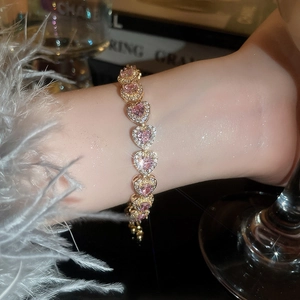 Detailed close-up of a pink heart-shaped crystal bracelet worn on a woman's wrist