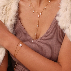 Détail du collier de perles en Y et du bracelet sur un mannequin avec manteau élégant