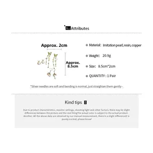 Detailed view of green butterfly tassel earrings and pearl studs with sizing details