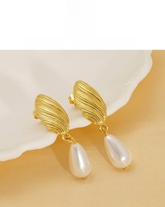 Detailed macro of 18K gold plated drop earrings with white pearls on a shell