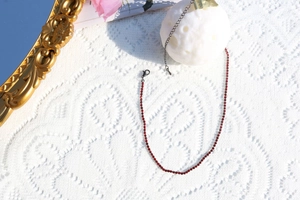 Macro detail of red rhinestone necklace with gunblack chain and lobster clasp closure