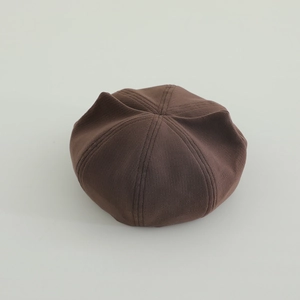 Top-down view showing star-shaped stitched panels of this brown wool beret for kids