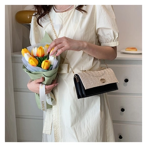 Detail of woven fabric handbag with black leather contrast and gold chain strap