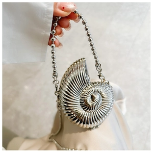 Detailed view of silver seashell evening clutch with pearl handle and spiral metal texture