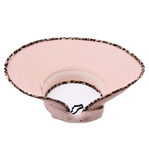 Close-up of pink straw sun hat with leopard trim and decorative bow detail