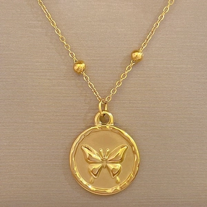 Detailed macro view of a gold titanium steel necklace with a round butterfly pendant