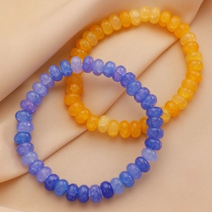 Gros plan de bracelets en perles de pierres naturelles et breloques papillon sur soie