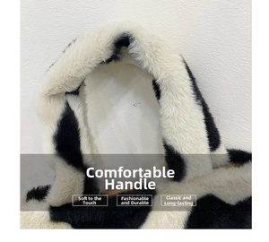 Detail of the widened comfortable handle on a cow print plush bucket handbag
