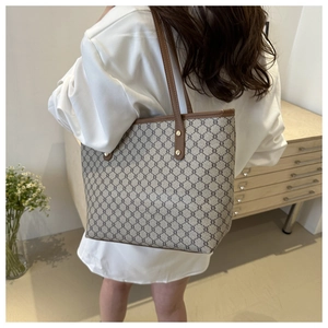 Close-up detail of monogram tote bag with leather handles and metallic rivet reinforcement