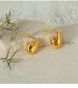 Detailed view of thick C-shaped 18K gold plated stud earrings with a high-polished finish