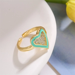 Detail view of a gold heart ring with mint green enamel and zircons on white ceramic