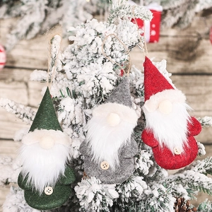Three Christmas gnomes hanging on a snowy tree with green, grey and red felt outfits