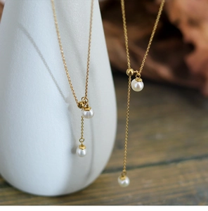 Detailed close-up of natural freshwater pearl tassels on a gold plated Y-shaped necklace
