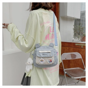 Detail of light blue crossbody canvas bag featuring bear ears and cute cartoon patches