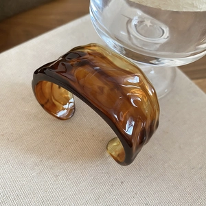 Macro detail of amber resin cuff bracelet with translucent wavy textures and brown swirl