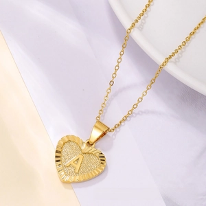 Close-up of heart-shaped gold pendant necklace with embossed letter A and detailed texture
