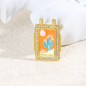 Macro view of gold rectangle pendant with orange enamel cactus and shimmering cubic zirconia
