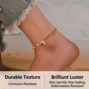 Close-up of double-layered gold anklet with star and moon charms on a beach